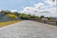 this is a photo of a long brick pathway that runs on a park bench and grass lawn