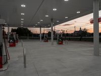 a gas station with three pumps on top of the gas pump platform and two empty bins beside them