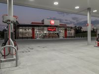 two gas pumps and a car wash station at dusk, with the awnings in bright light