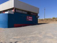 a sign on the side of a building by a desert road with a truck parked behind it