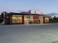 a food court with an exterior and entrance lit up at night with sky light on the ground