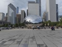 a crowd is gathering in a big public plaza near city buildings that have mirrored windows