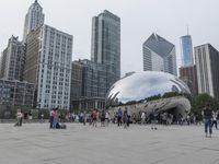 a crowd is gathering in a big public plaza near city buildings that have mirrored windows