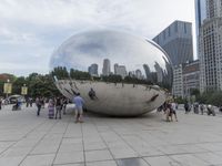 a crowd is gathering in a big public plaza near city buildings that have mirrored windows