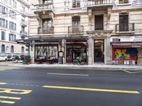 a city street with a store on the side of it and a building across the street with balconies