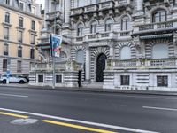 a black fire hydrant in the middle of a street in front of a large stone building