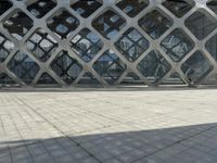 the concrete floor outside of an architectural building with geometric designs on it, along with a stone walkway and glass wall