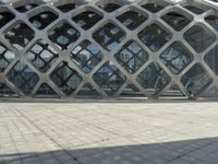 the concrete floor outside of an architectural building with geometric designs on it, along with a stone walkway and glass wall