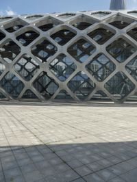the concrete floor outside of an architectural building with geometric designs on it, along with a stone walkway and glass wall