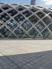the concrete floor outside of an architectural building with geometric designs on it, along with a stone walkway and glass wall