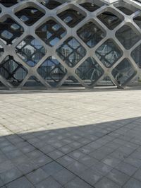 the concrete floor outside of an architectural building with geometric designs on it, along with a stone walkway and glass wall