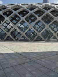 the concrete floor outside of an architectural building with geometric designs on it, along with a stone walkway and glass wall