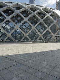 the concrete floor outside of an architectural building with geometric designs on it, along with a stone walkway and glass wall