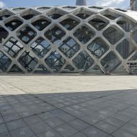 the concrete floor outside of an architectural building with geometric designs on it, along with a stone walkway and glass wall