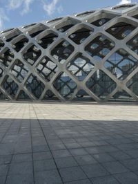 the concrete floor outside of an architectural building with geometric designs on it, along with a stone walkway and glass wall