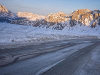 a person riding on the road in the middle of a snow covered landscape with mountains