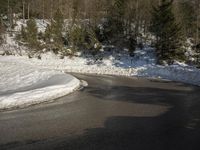 a road surrounded by snow covered trees on a sunny day with blue sky above in the background