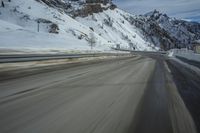a blurry shot of a snow covered mountain road, with snow covered mountains in the background
