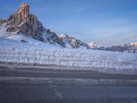 a lone person rides his motorcycle along the snow with mountains in the background with deep blue sky