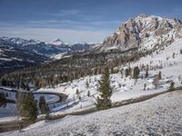 this is a wide wide snowy road in the mountains, which winds up and makes its way down to the mountain top