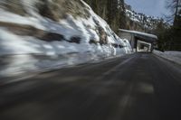 an abstract photograph of a speeding car on a snowy hill road while snow drifts the walls and mountains
