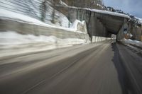 an abstract photograph of a speeding car on a snowy hill road while snow drifts the walls and mountains