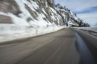 an abstract photograph of a speeding car on a snowy hill road while snow drifts the walls and mountains