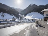 a mountain village with many houses covered in snow and surrounded by mountains and trees, snow is on the ground