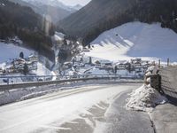 a mountain village with many houses covered in snow and surrounded by mountains and trees, snow is on the ground