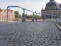 the empty street near a building has a blue pole and some bicycles on it to keep it organized