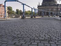 the empty street near a building has a blue pole and some bicycles on it to keep it organized