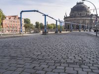 the empty street near a building has a blue pole and some bicycles on it to keep it organized