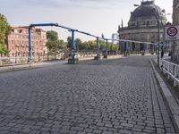 the empty street near a building has a blue pole and some bicycles on it to keep it organized