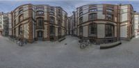 an artistic perspective of a residential building near other buildings and bicycles on the street in front of them