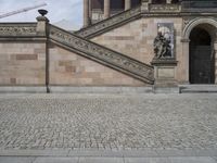 a person is standing on a walkway with an umbrella over their head looking towards the stairs