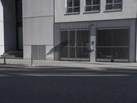 a tall white building on a city street next to the curb with an open door