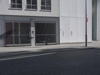 a tall white building on a city street next to the curb with an open door