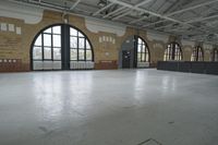 an empty warehouse with many windows, brickwork and cement flooring, has white floors