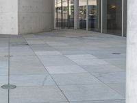 a person on a skateboard stands in front of a building with many glass doors