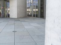 a person on a skateboard stands in front of a building with many glass doors