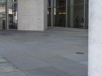 a person on a skateboard stands in front of a building with many glass doors