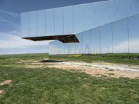 an overexposed building is made up of many mirrors on the ground in a field