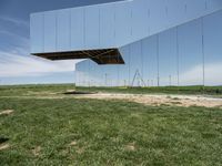 an overexposed building is made up of many mirrors on the ground in a field