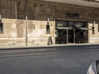 an old stone building next to a sidewalk with a traffic light in front of it