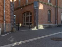 a picture of a street next to a red brick building that is built into the side of a hill