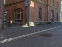 a picture of a street next to a red brick building that is built into the side of a hill