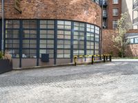 the back of an old red brick building is near many plants and trees in front of it