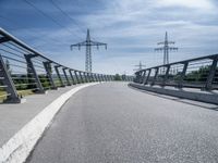 power lines above a walkway at a bridge with bike on the left side and sky above