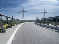 power lines above a walkway at a bridge with bike on the left side and sky above