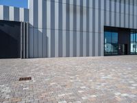 a brick walkway outside of a business building, with a large windowed front door